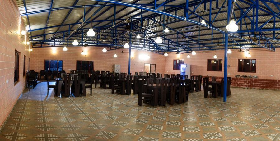 Expansive covered dining hall pavilion with banquet tables and tiled flooring in Rishikesh
