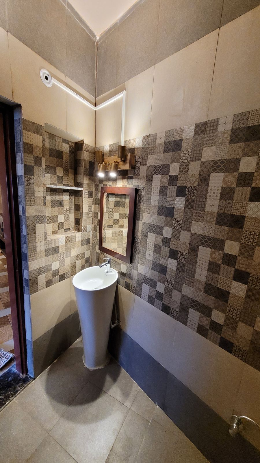 Stylish tiled bathroom with round vanity sink and mirror in Bhimtal