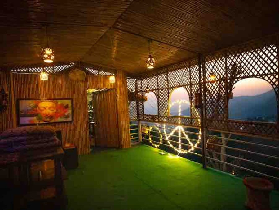 Bamboo-thatched rooftop lounge framing mountain valley scenery in Rishikesh.
