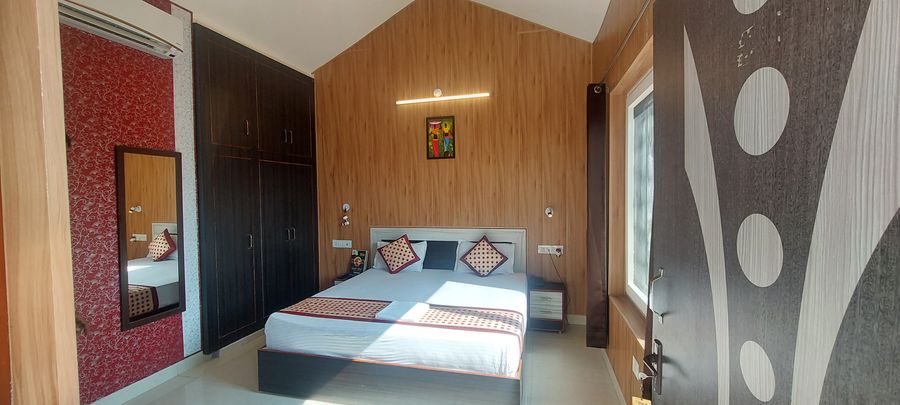 Deluxe cottage bedroom featuring vaulted wood-paneled walls, double bed, and wardrobe in Rishikesh