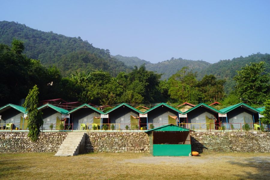 Riverside camping grounds with mountain foothills backdrop in Rishikesh