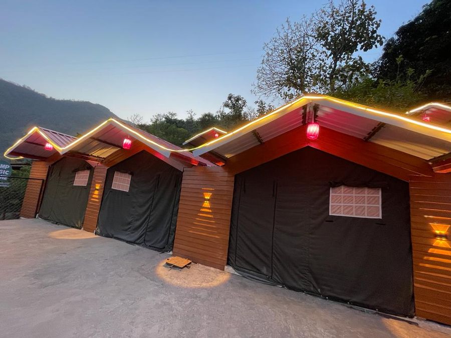 Row of pitched-roof cottage fronts accented with warm roofline illumination in Rishikesh
