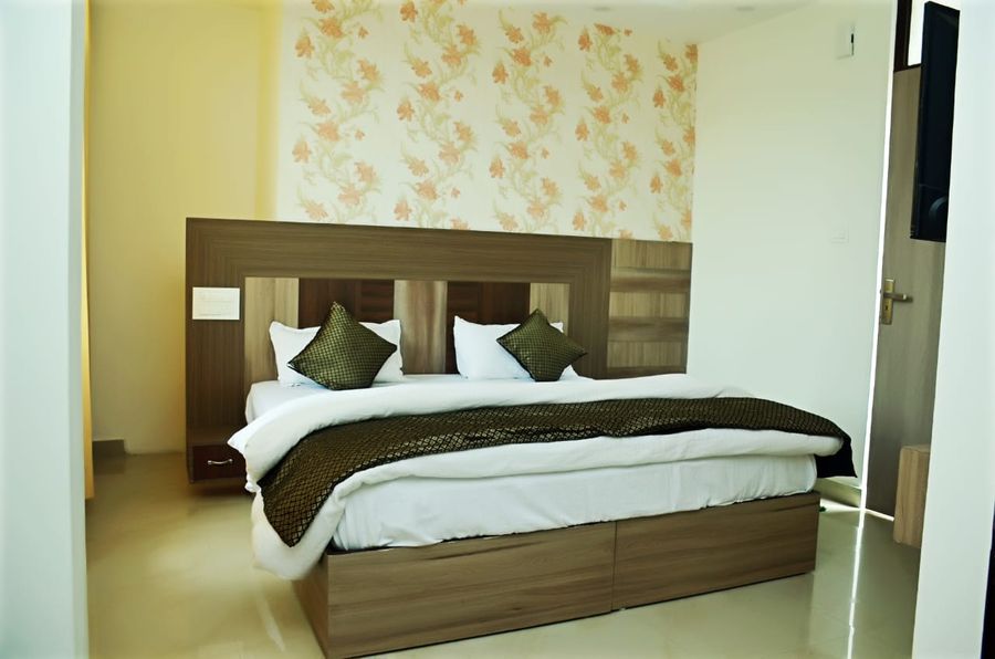 Comfortable double bed with wooden headboard and accent wallpaper in Kasauli
