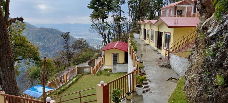 Hillside cottage pathway and garden lawn overlooking panoramic mountain valley views in Rishikesh