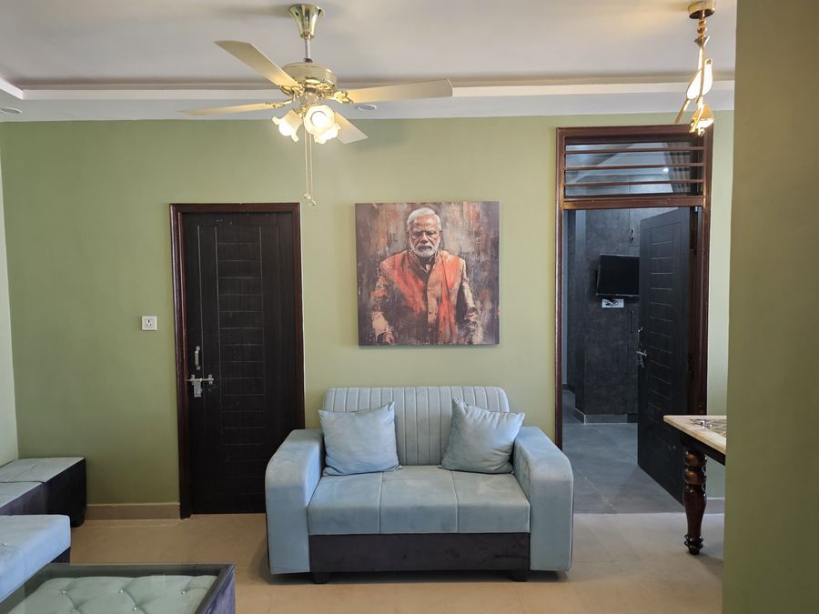 Cozy living area arrangement highlighting sofa seating, ceiling fan, and wall portrait in Rishikesh