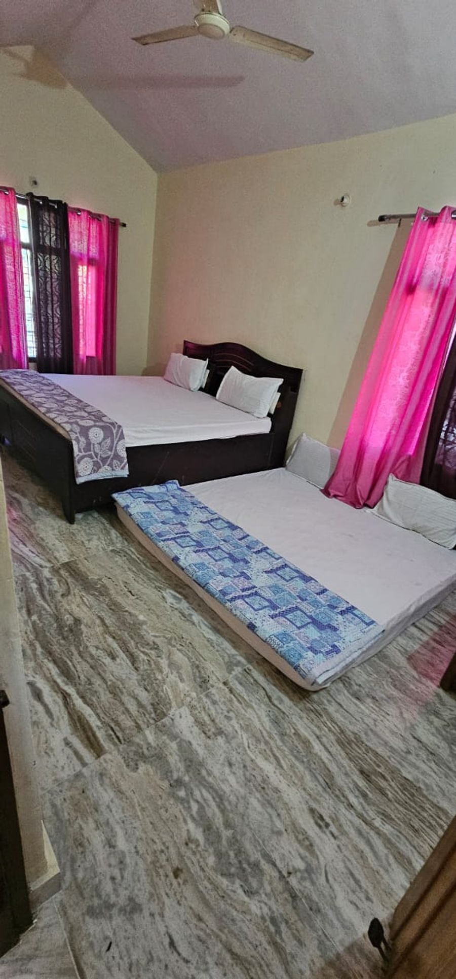 Spacious bedroom layout with primary bed and extra floor mattress in Bhimtal
