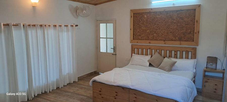 Bright bedroom with natural wood finishes and double bed in Bhimtal