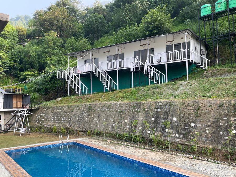 Elevated hillside cottage huts overlooking the outdoor swimming pool deck in Rishikesh