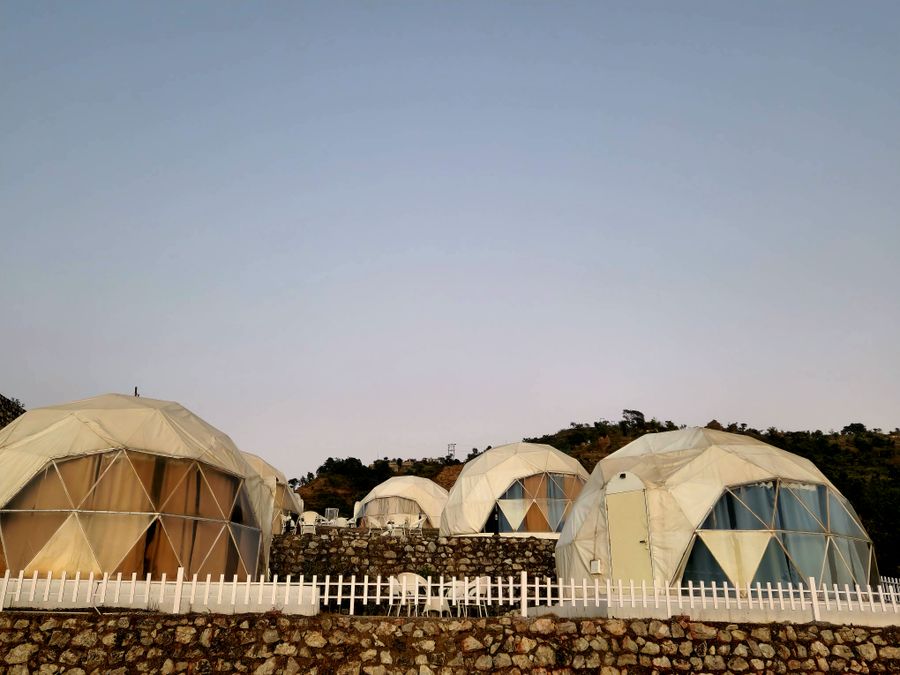 Cluster of geodesic dome tents set against clear mountain skies in Rishikesh