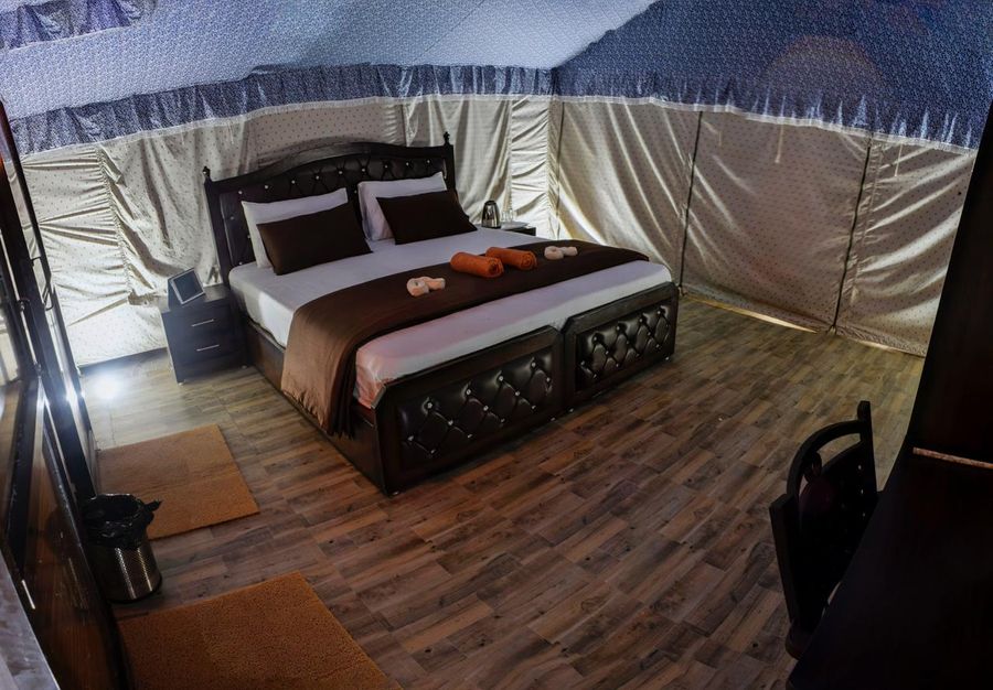 Glamping tent interior featuring a polished wooden double bed and bedside tables in Rishikesh