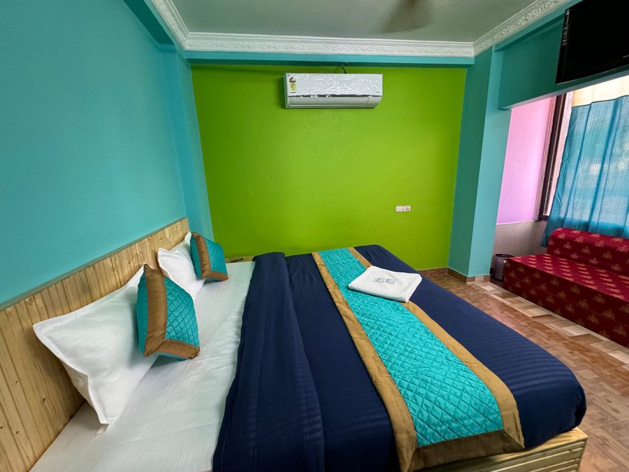 Vibrant green-accented bedroom with air conditioning and seating sofa in Rishikesh