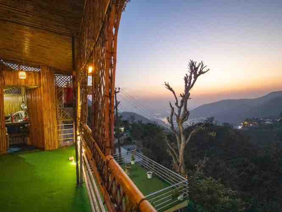 Bamboo-clad balcony sit-out with artificial grass overlooking the sunset hills in Rishikesh.