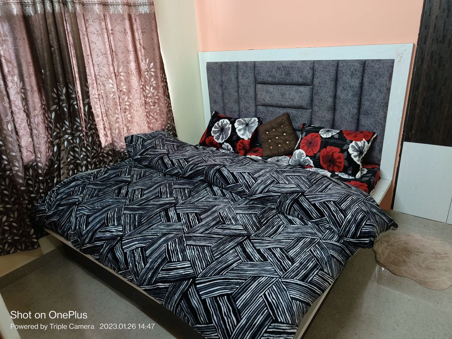 Warm homestay bedroom with dark accent headboard in Kasauli