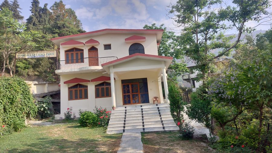 Standalone multi-story cottage facade with front steps and garden in Bhimtal