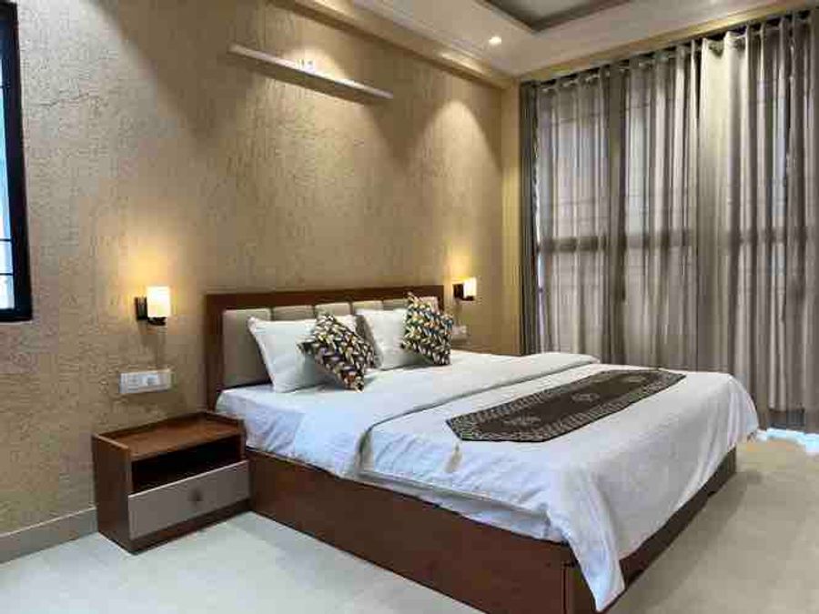 Warm bedroom suite with double bed and draped windows in Bhimtal