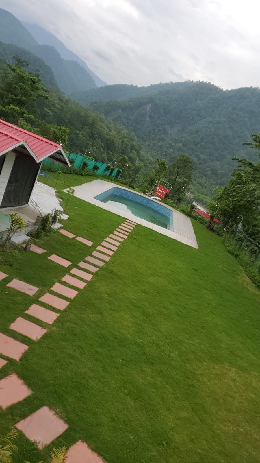 Aerial view of lush manicured garden lawn and outdoor swimming pool in Rishikesh