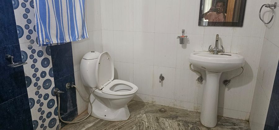 Attached washroom with shower curtain, pedestal basin, and western toilet in Bhimtal