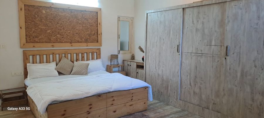 Spacious master bedroom with wooden bed and wardrobe in Bhimtal