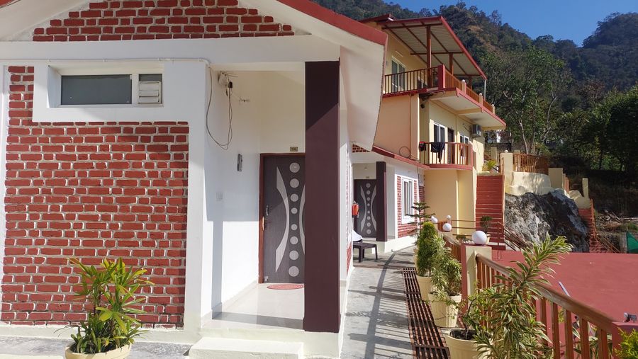 Brick-accented cottage exterior and entrance walkway along the mountain slope in Rishikesh