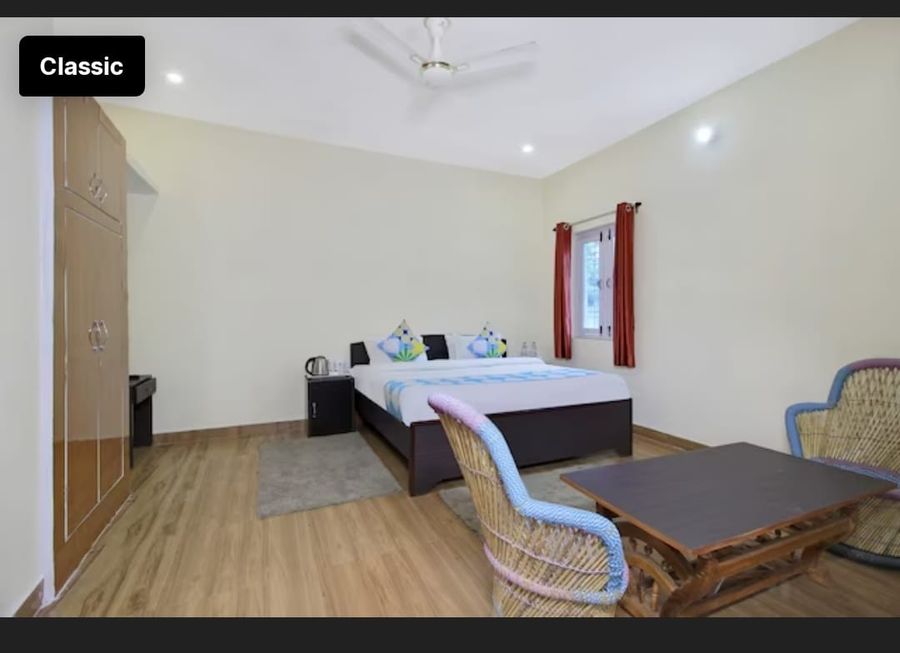 Spacious bedroom suite with wooden flooring and seating area in Bhimtal
