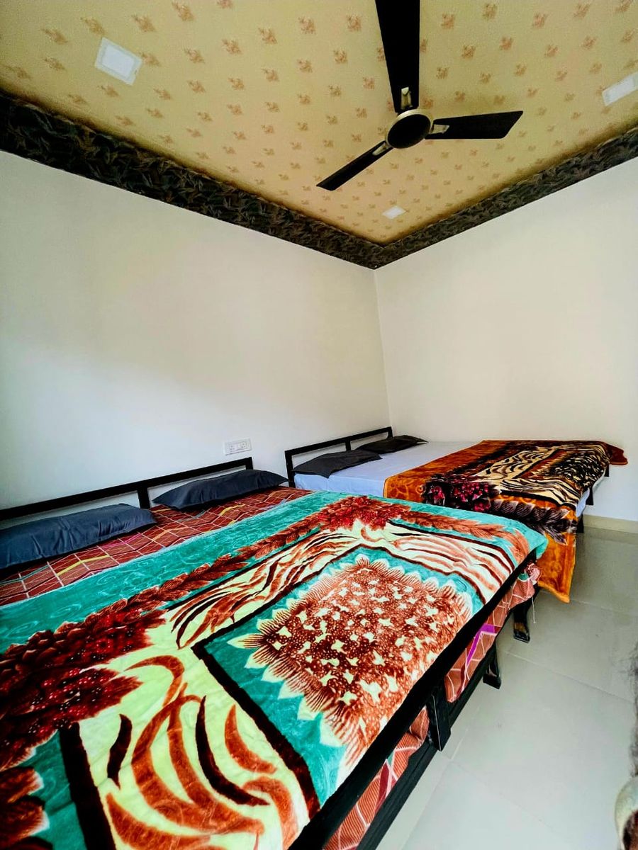 Multi-bed guest room setup with colorful printed blankets in Rishikesh