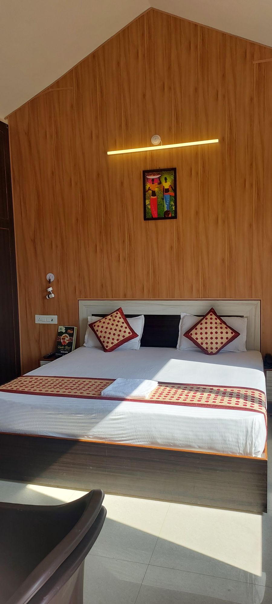Cozy cottage double bed setup with wood-clad accent wall and patterned throw pillows in Rishikesh