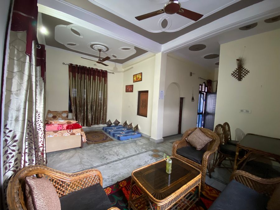Spacious open-plan living room with false ceiling and tiled floor in Rishikesh