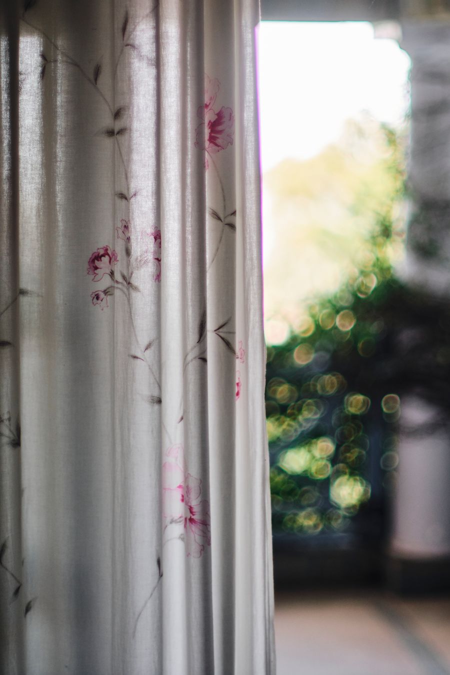 Floral curtain window framing lush greenery outside in Kasauli