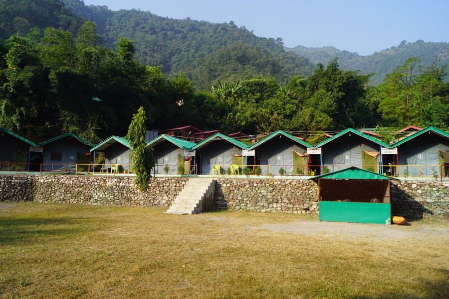 Spacious open campsite lawn framed by row of safari tents in Rishikesh