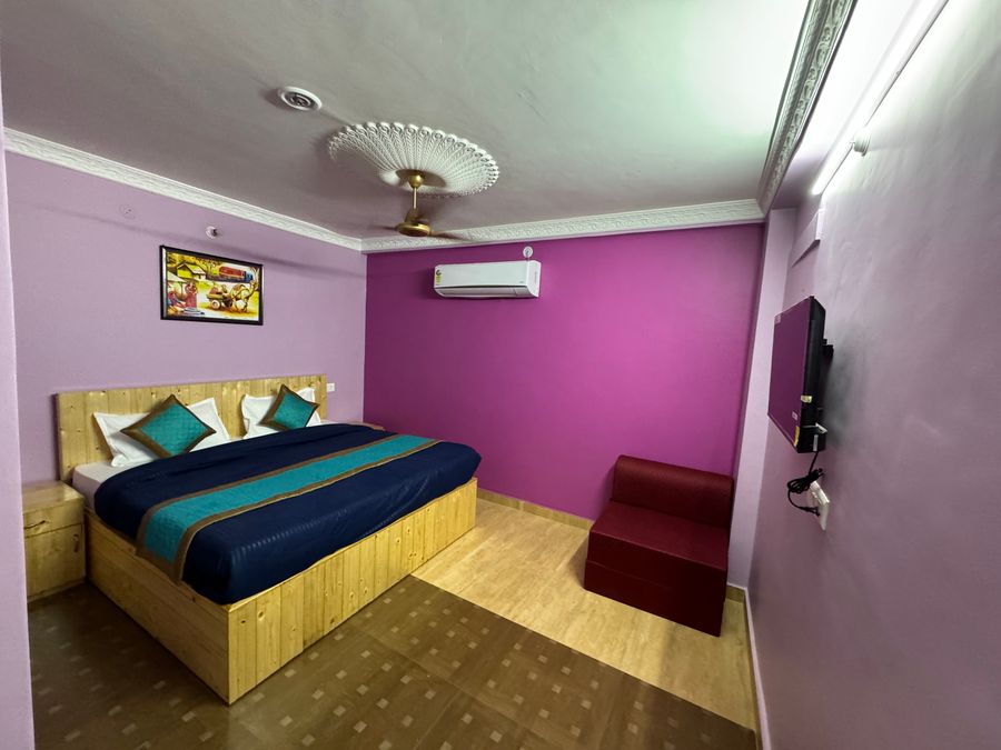 Spacious guest room with purple accent wall, air conditioner, and double bed in Rishikesh