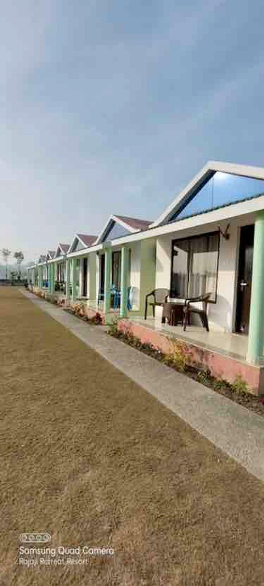 Row of modern white cottages with pitched roofs and front patio seating in Rishikesh