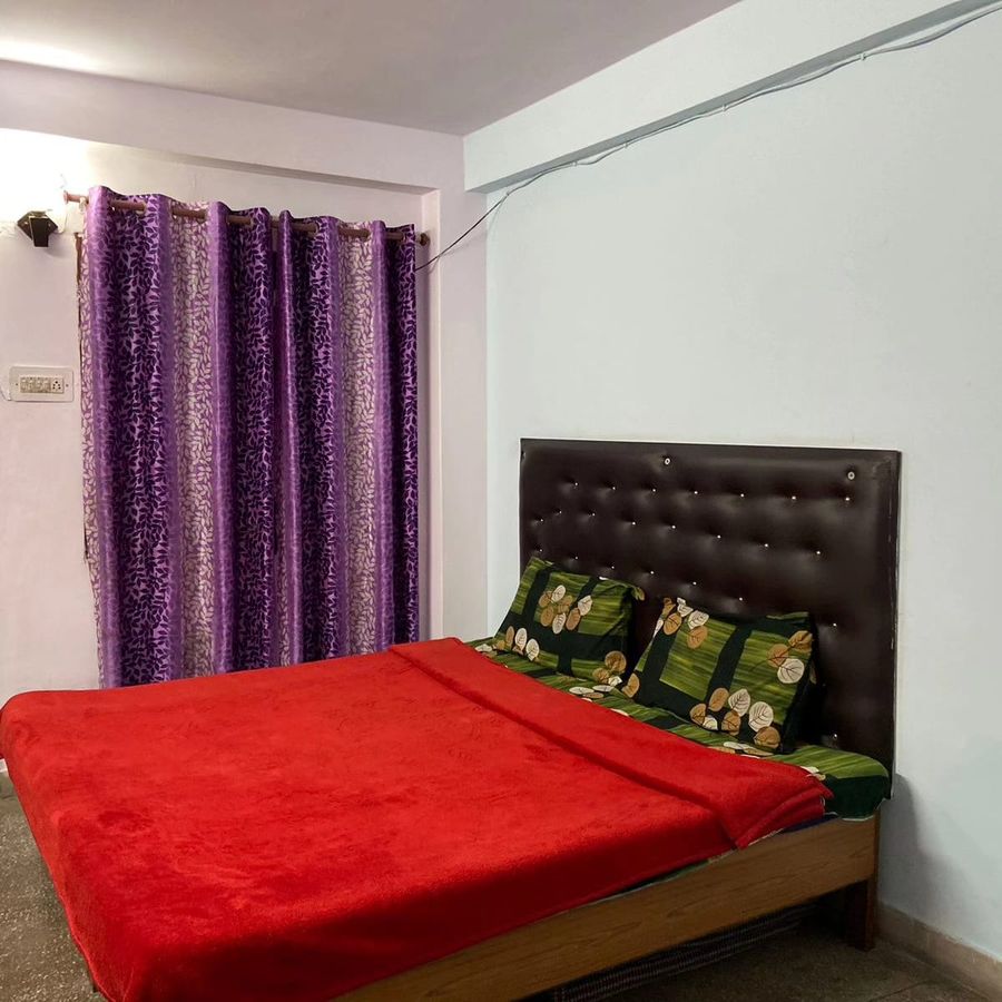 Cozy master bedroom with red bed at sunny home stay