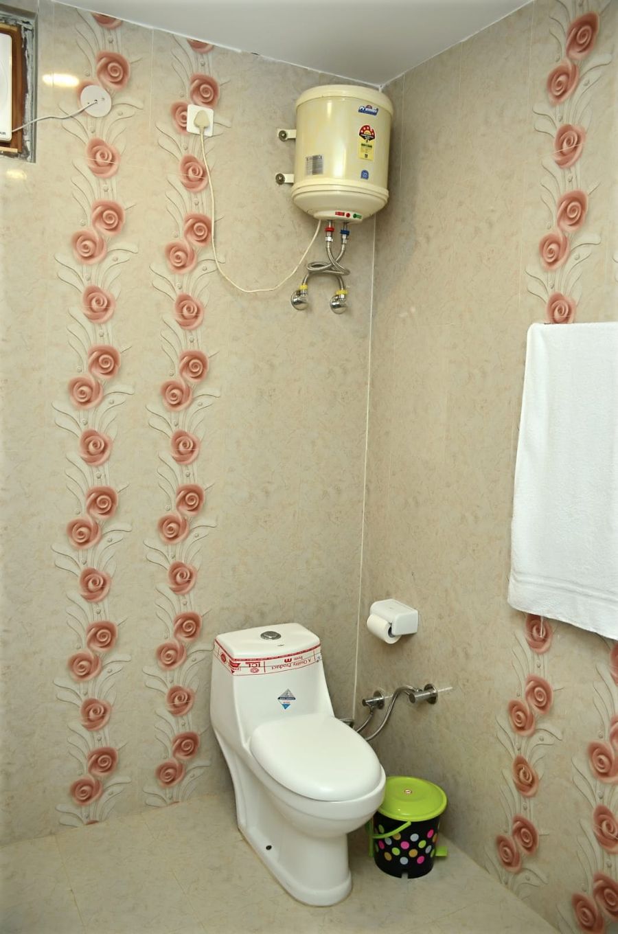 Clean tiled bathroom with wall shower and towel rail in Kasauli
