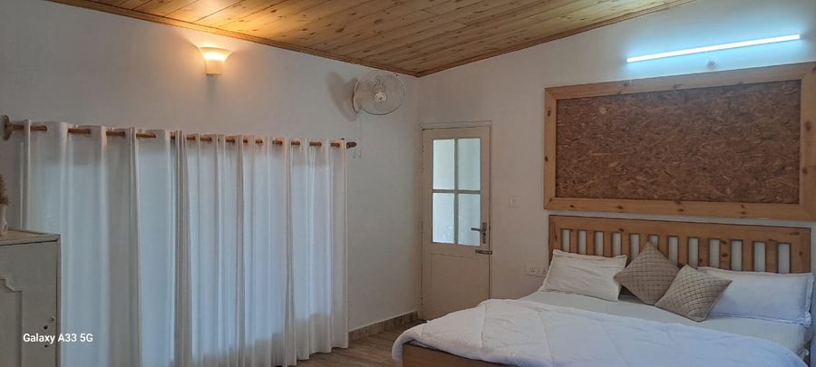 Cozy rustic bedroom with wooden ceiling and white drapery in Bhimtal