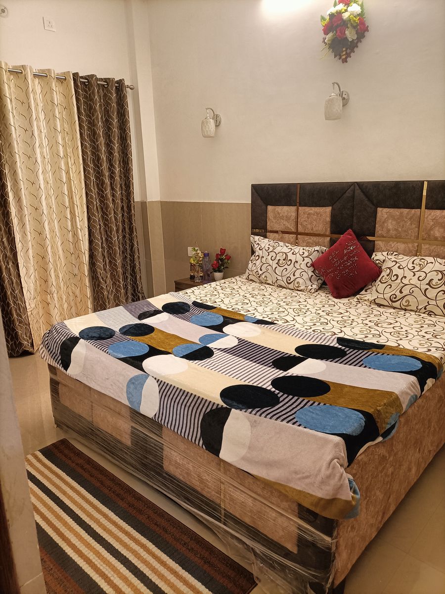 Cozy double bedroom setup with patterned linens and curtains in Rishikesh