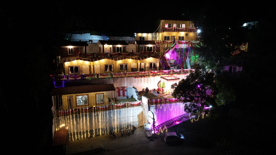 Multi-tiered hillside resort exterior brightly lit with vibrant night lights in Rishikesh