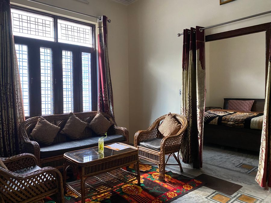 Cozy living room lounge with cane sofa set and coffee table next to curtained window in Rishikesh