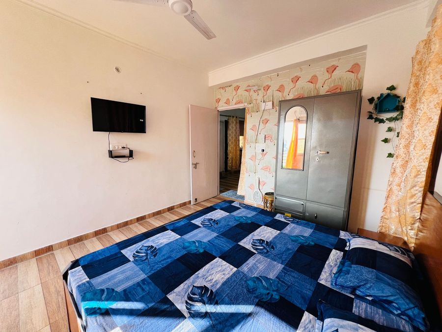 Spacious guest bedroom with blue patterned bedding and steel almirah wardrobe in Rishikesh