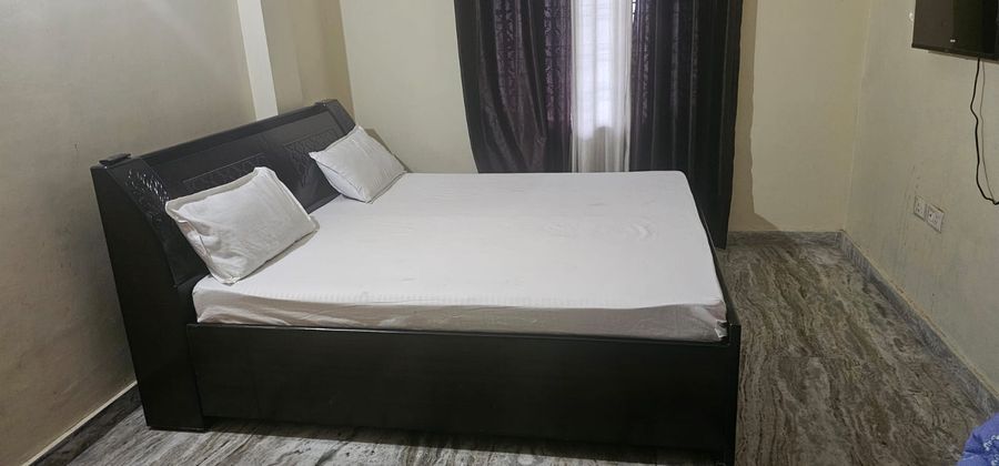 Neat bedroom with comfortable double bed and curtained window in Bhimtal