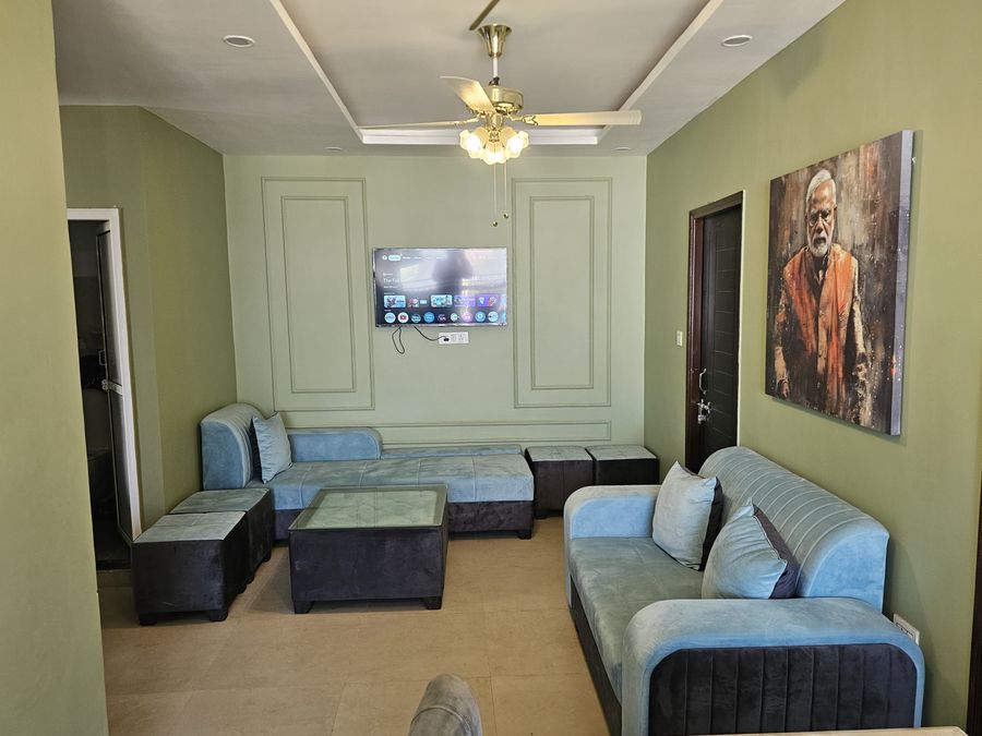 Spacious living room setup featuring sectional sofa seating, wall art, and TV unit in Rishikesh