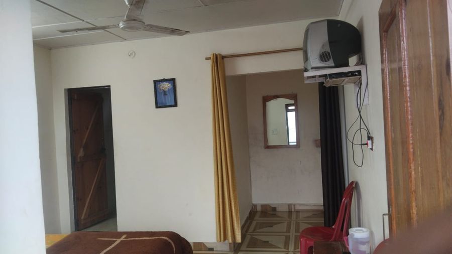 Spacious guest room layout with dressing mirror and doorway in Bhimtal