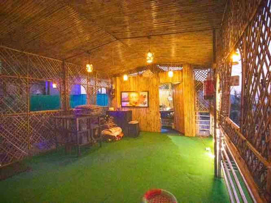 Semi-open rooftop café pavilion with colorful evening lighting and bamboo furniture in Rishikesh.