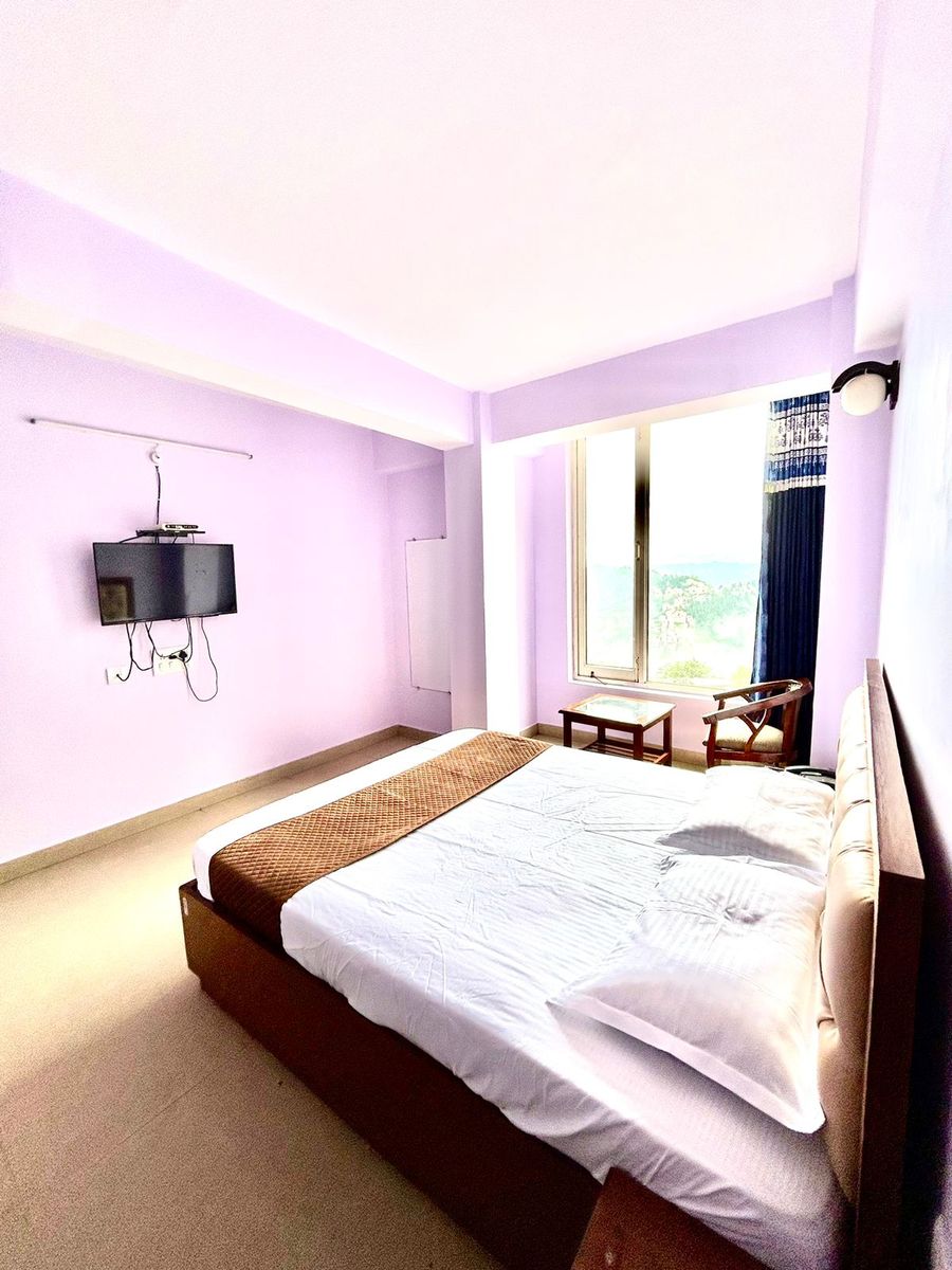 Wall mounted television and double bed view at hotel in shimla