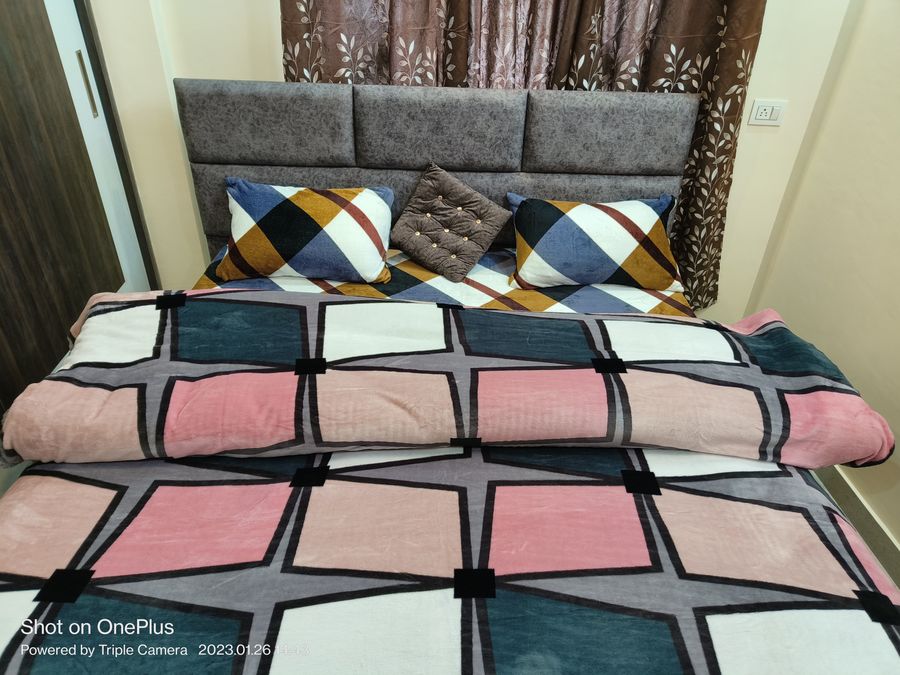 Neatly made double bed with colorful printed comforter Kasauli