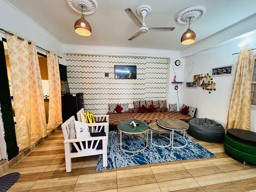 Open lounge space with decorative chevron wallpaper, seating chairs, and pendant lighting in Rishikesh