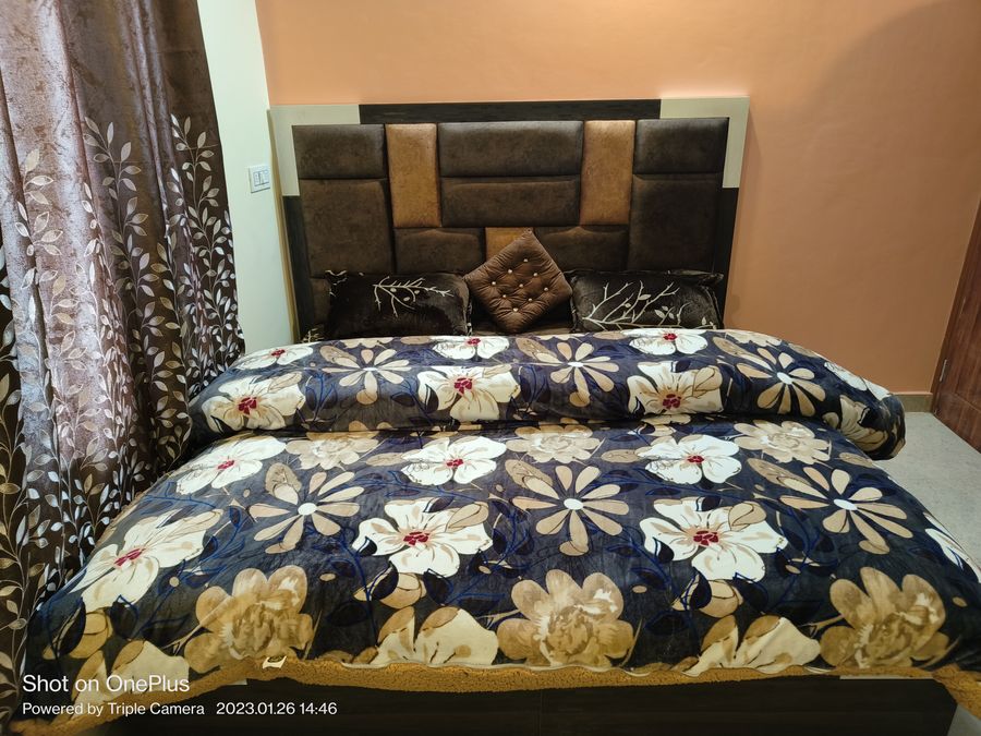 Double bed with floral quilt and cushioned headboard in Kasauli