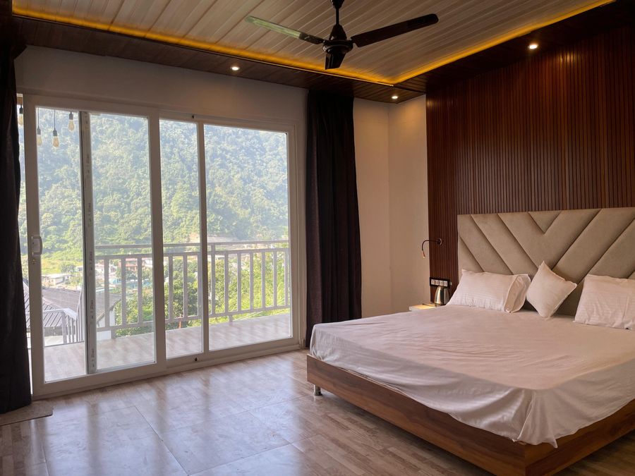 Bright bedroom suite with large sliding glass doors framing mountain views in Rishikesh