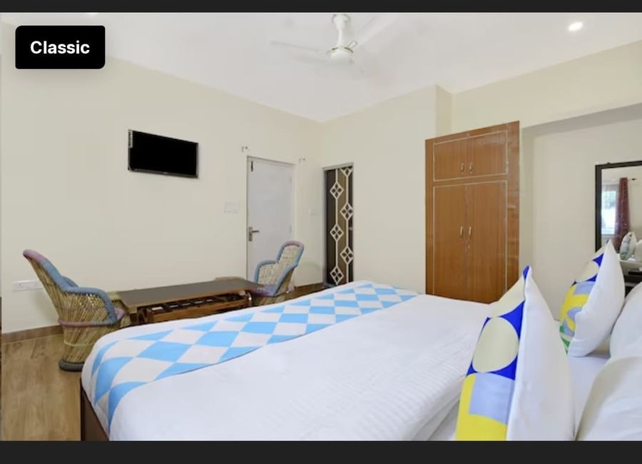 Sunlit guest room featuring comfortable bedding and cane chairs in Bhimtal