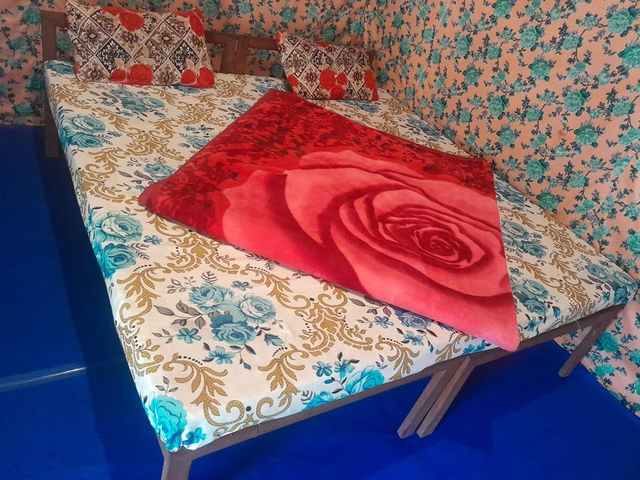 Clean tent bed setup with floral patterned blankets in Rishikesh