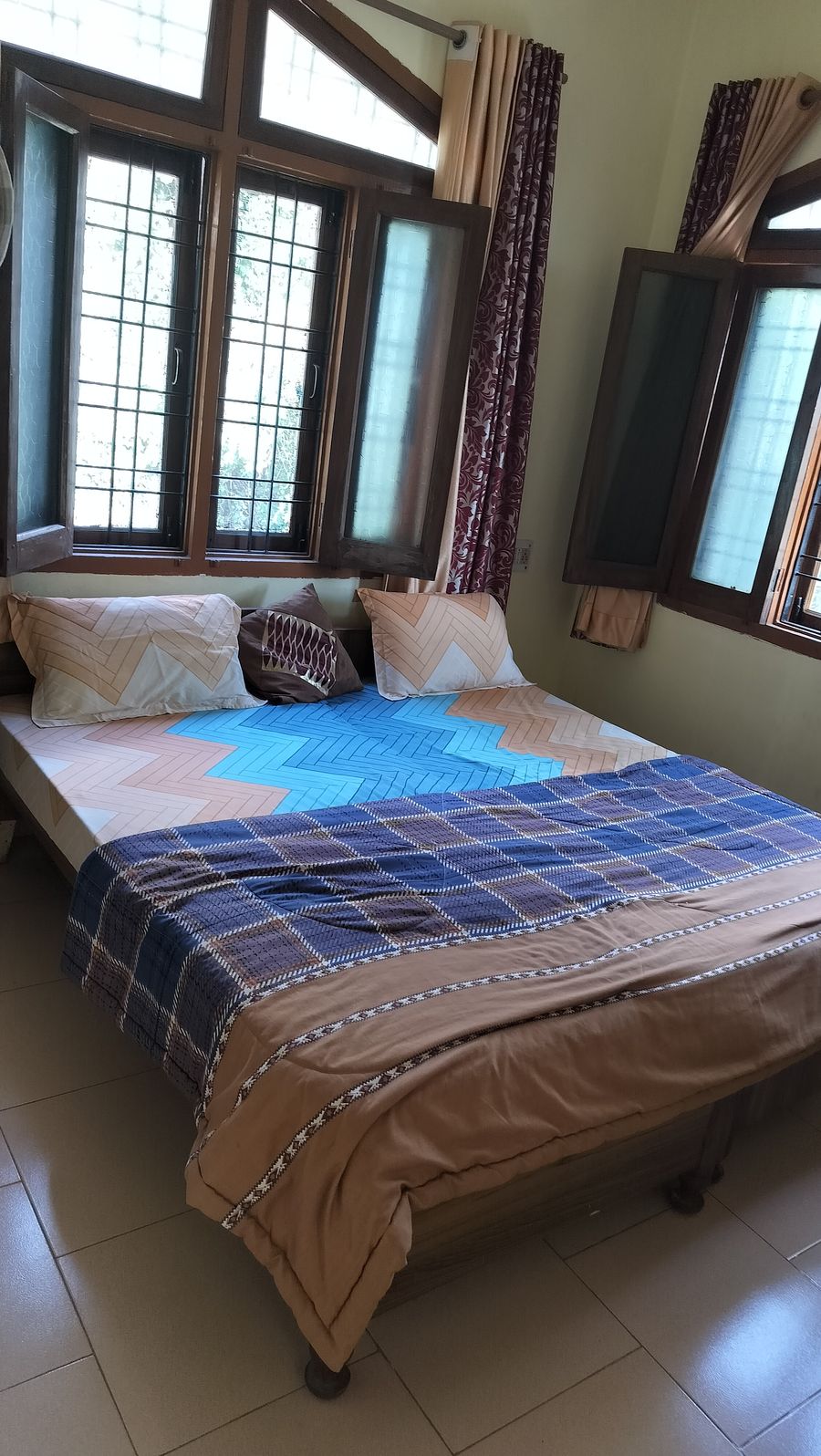 Comfortable double bed with colorful chevron sheets and pillows in Bhimtal